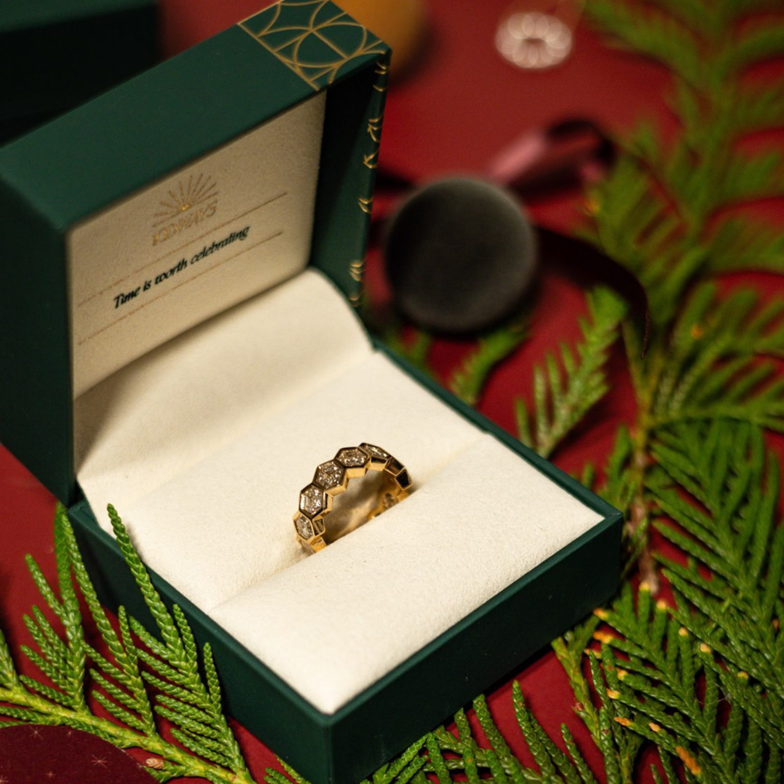 Hexagon setting diamond eternity, wedding band in an open green 100 Ways jewellery box with festive greenery.