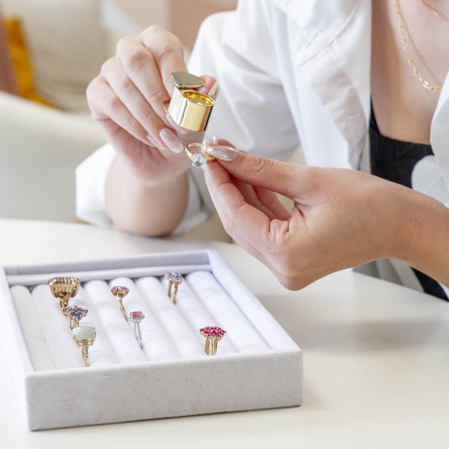 image of woman viewing a selection of vintage rings in a velvet tray at a 100 ways showroom appointment using a loop magnifier