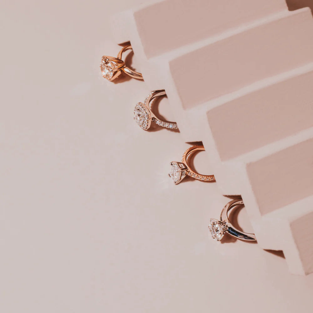 a selection of engagement rings on a pink background styled with a step prop 