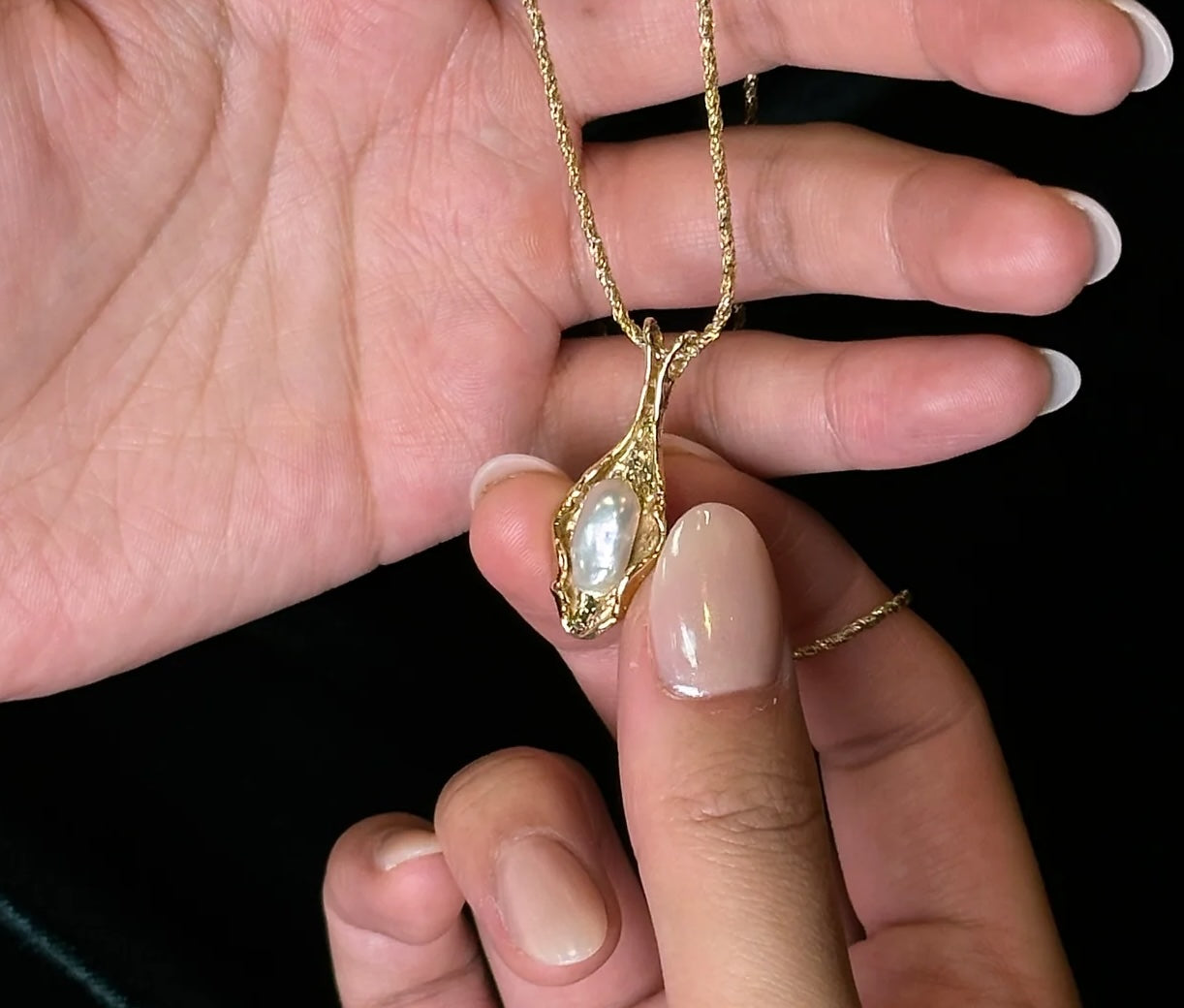 image of pearl pendant necklace, cultured pearl being held in manicured hands