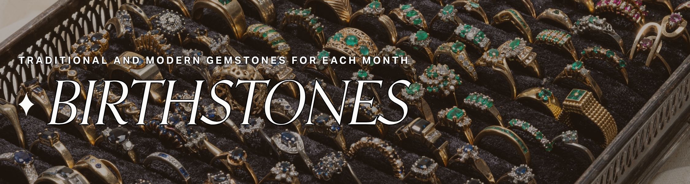 Vintage jewellery tray displays collection of rings with colourful gemstones, text overlay reads: traditional and modern gemstones for each month birthstones