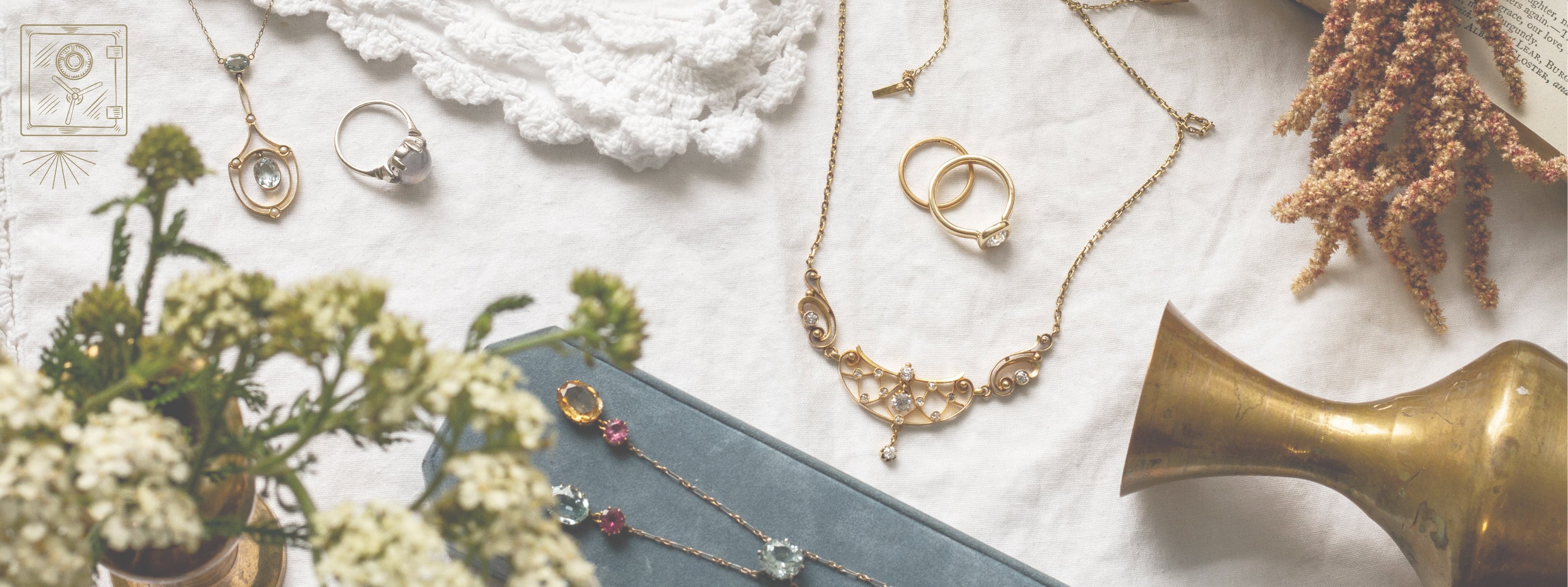 image of vintage and antique jewelry styled on a linen tablecloth with decor pieces, image overlay shows a vault with starburst