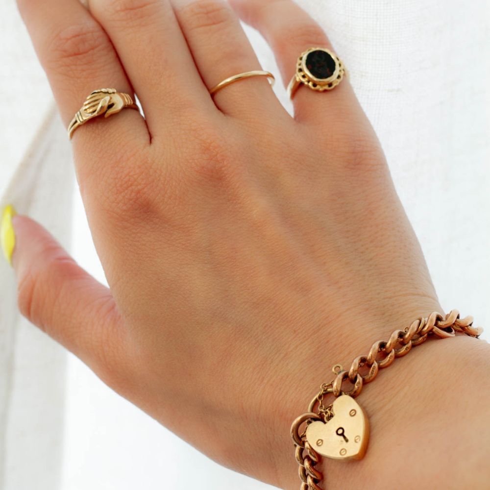 image of woman's hand opening curtains, wearing vintage rings and bracelet.